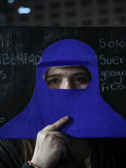 Chilenische Frau hält einen blauen Papkarton in Form einer Vollverschleierung vor ihr Gesicht als Protest gegen einen Gesetzentwurf, der vorsieht, dass Frauen vor einer Abtreibung den Herzschlag des Babys anhören müssen. 