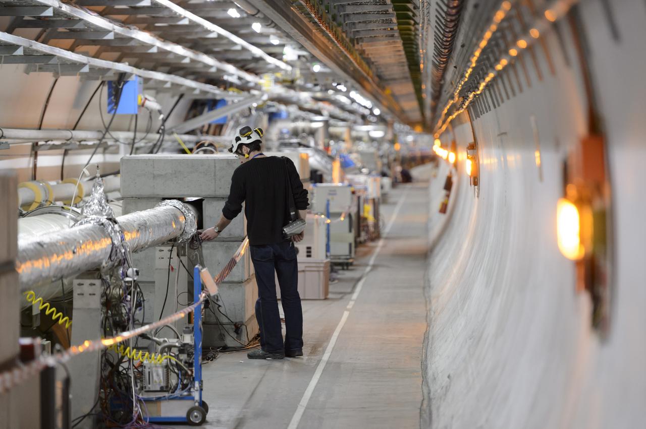 Mensch in einem Tunnel mit vielen technischen Geräten: Techniker arbeiten im LHC-Tunnel der Europäischen Organisation für Kernforschung.