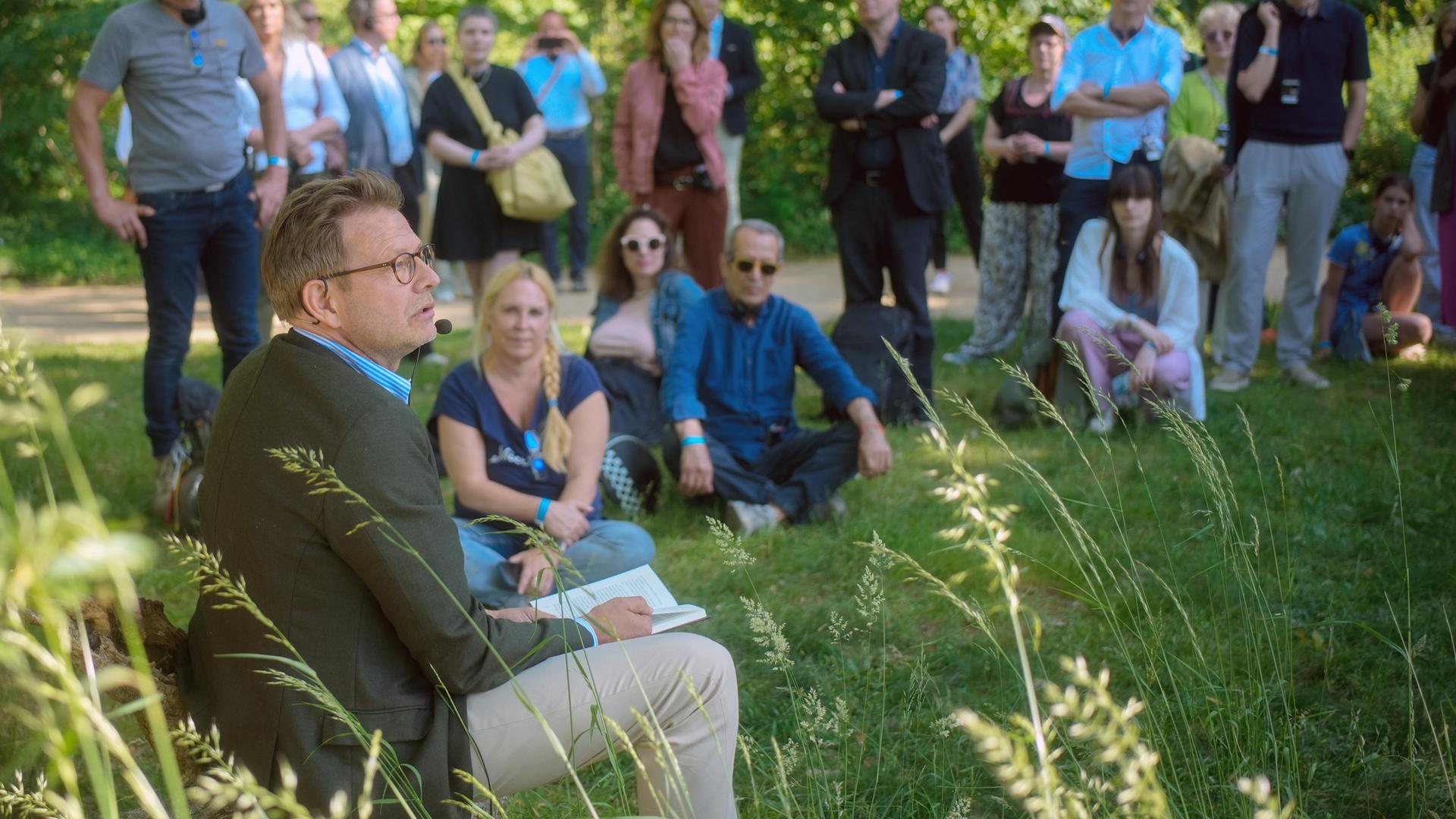 Bestsellerautor Florian Illies liest bei einem Pressetermin aus seinem Buch. Er und seine Gäste sitzen auf einer Wiese auf der Pfaueninsel.