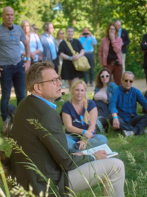 Bestsellerautor Florian Illies liest bei einem Pressetermin aus seinem Buch. Er und seine Gäste sitzen auf einer Wiese auf der Pfaueninsel.