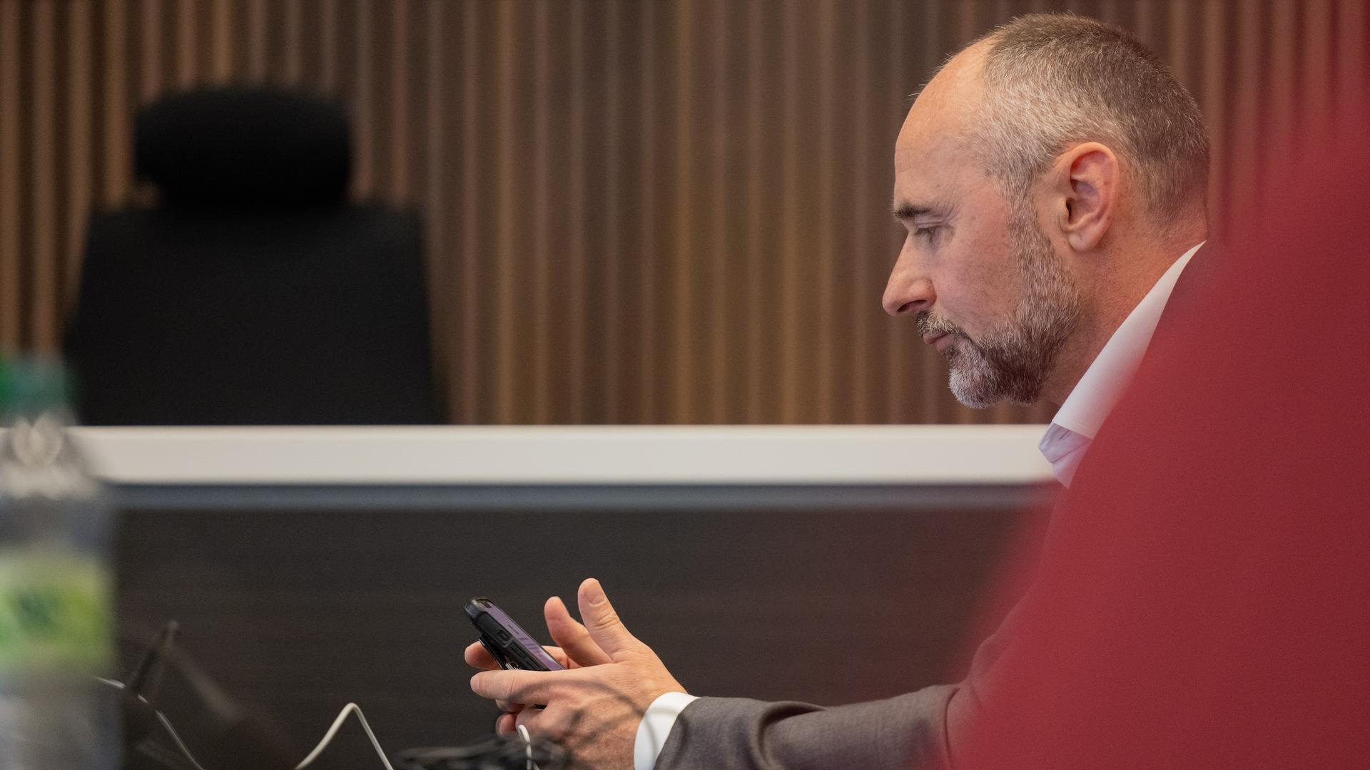 Der angeklagte Rechtsanwalt Kai-Uwe Steck sitzt im Gerichtssaal der Außenstelle des Landgerichts Bonn. Er schaut auf sein Handy. Der angeklagte Rechtsanwalt Kai-Uwe Steck sitzt im Gerichtssaal der Außenstelle des Landgerichts Bonn. Er schaut auf sein Handy.