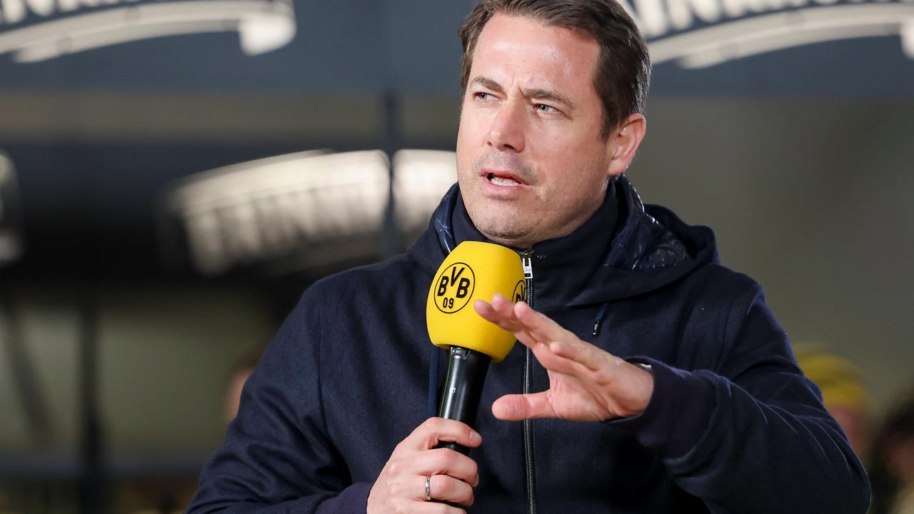 Lars Ricken spricht in ein gelbes Mikrofon mit BVB-Logo.