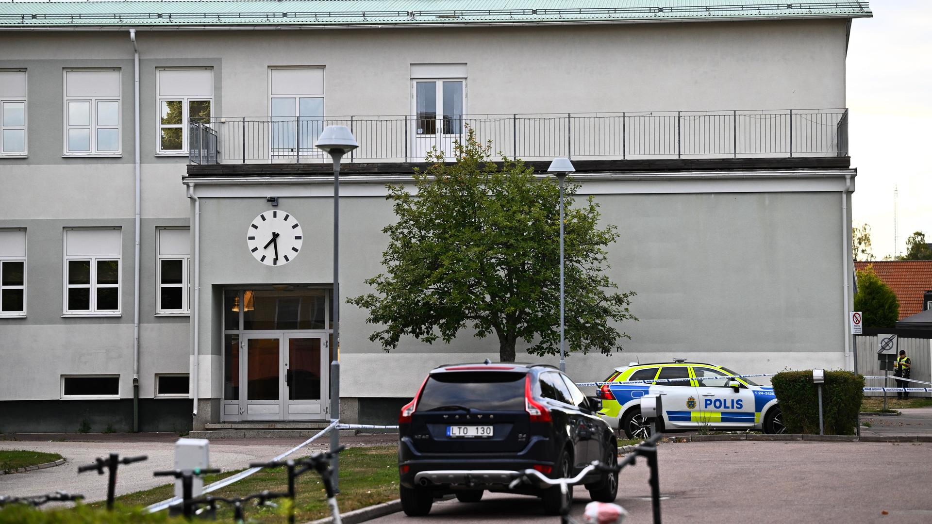 Nach dem Angriff in einer Schule in Fagersta: ein Polizeiauto steht vor dem Gebäude, rechts daneben sind Polizisten zu sehen. Nach dem Angriff in einer Schule in Fagersta: ein Polizeiauto steht vor dem Gebäude, rechts daneben sind Polizisten zu sehen.