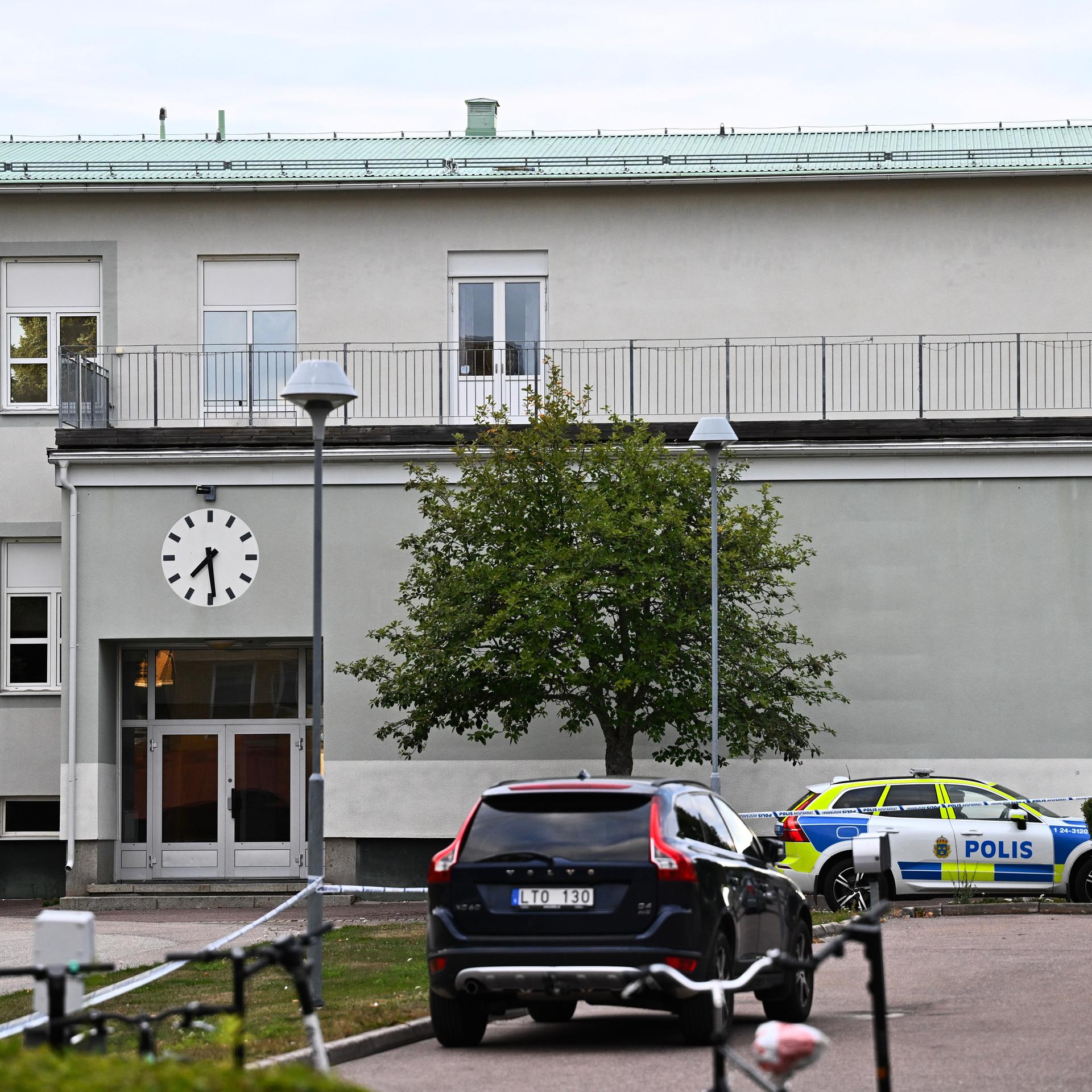 Nach dem Angriff in einer Schule in Fagersta: ein Polizeiauto steht vor dem Gebäude, rechts daneben sind Polizisten zu sehen.