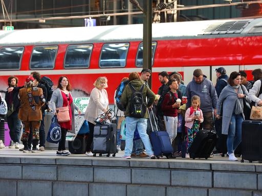 Fahrgäste warten am Hamburger Hauptbahnhof auf ihren Zug. Im Hintergrund ist ein Regionalexpress zu sehen.