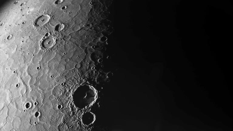 Das Bild zeigt eine Schwarz-Weiß-Aufnahme des Merkur. Es sind Krater und Gebirge zu erkennen.