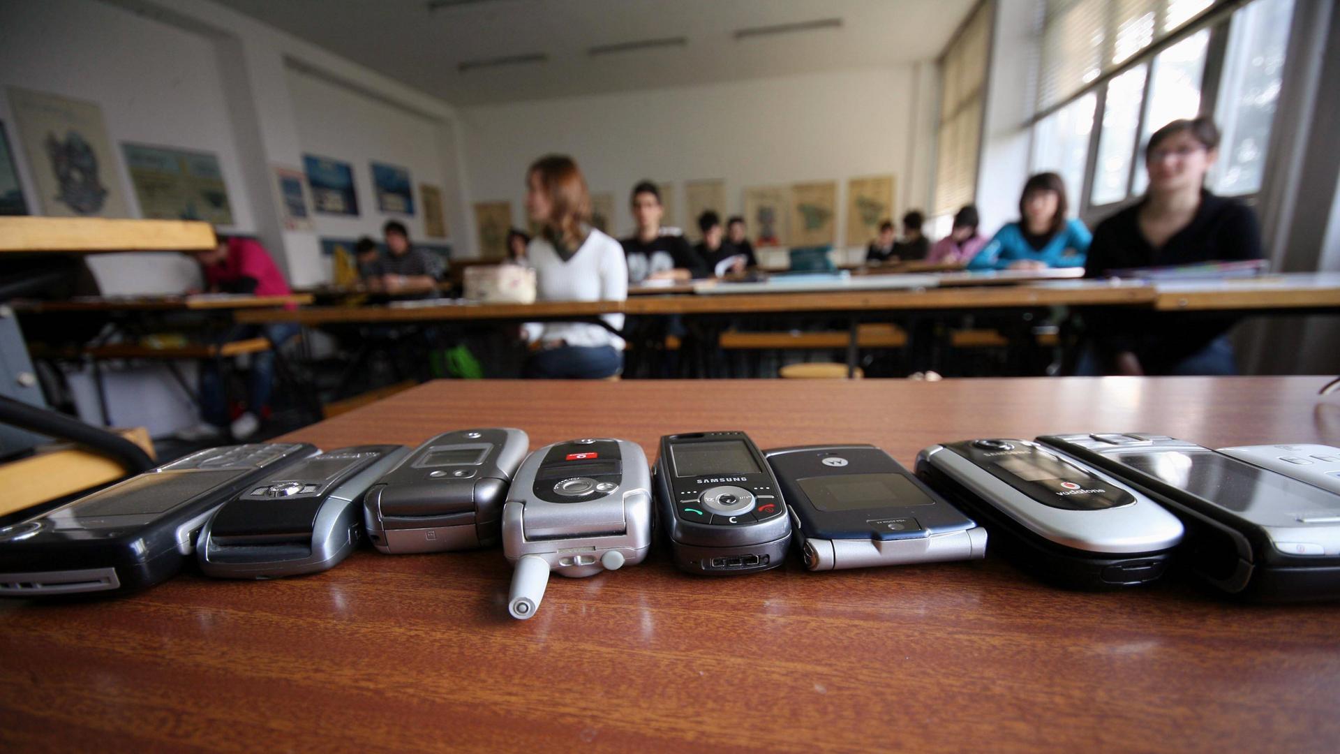 Handys liegen auf einem Tisch in einer Klasse in Brescia, Italien. Handys liegen auf einem Tisch in einer Klasse in Brescia, Italien.