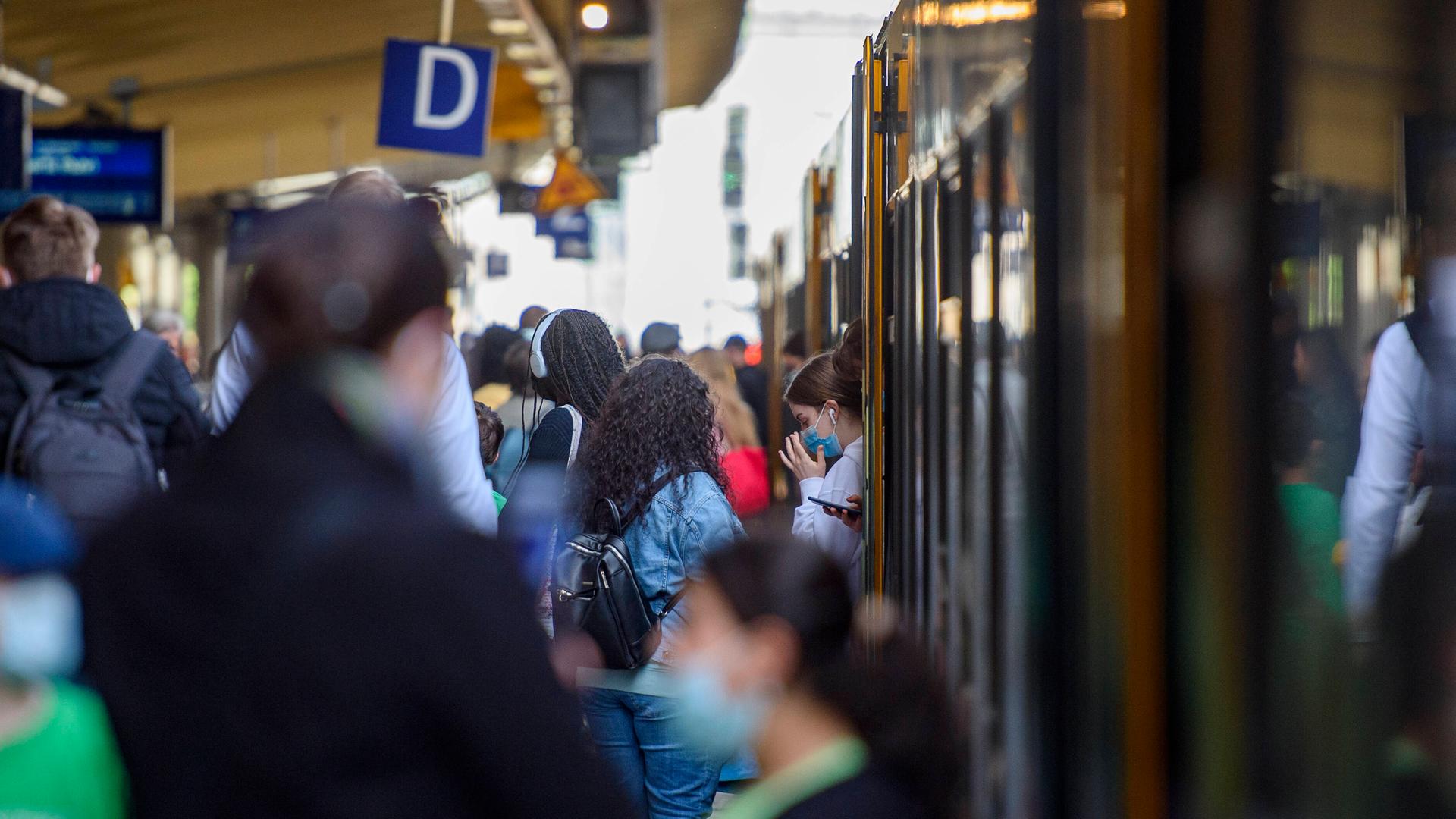 Ein Zug steht in Wuppertal an einem Gleis, Menschen steigen ein und aus.