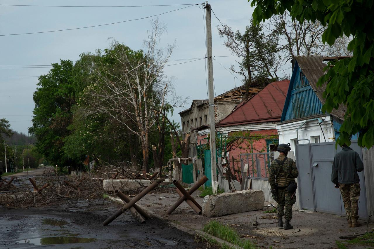 Zwei Soldaten gehen an einer Straße in der Nähe der Stadt Isjum entlang, auf der Sperren aufgebaut sind.