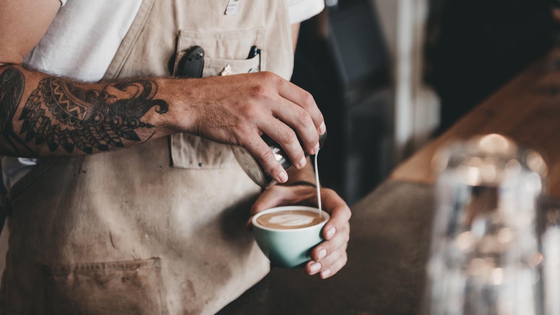 Ein Barista bereitet einen Kaffee mit Latte Art zu. 