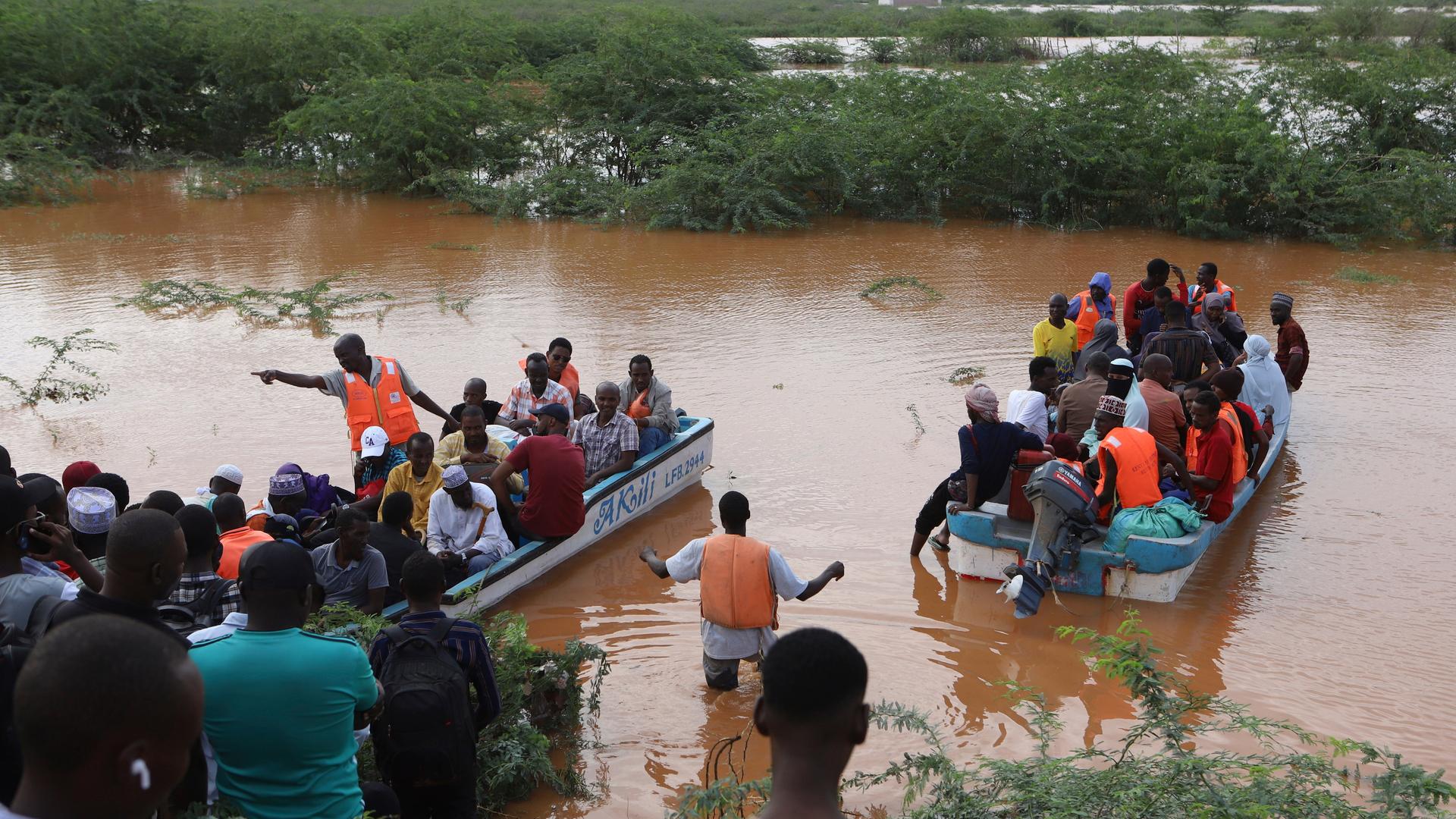 Im Nordosten Kenias überqueren Menschen mit einem Boot ein überflutetes Gebiet, in dem ein anderes Boot gekentert ist. 