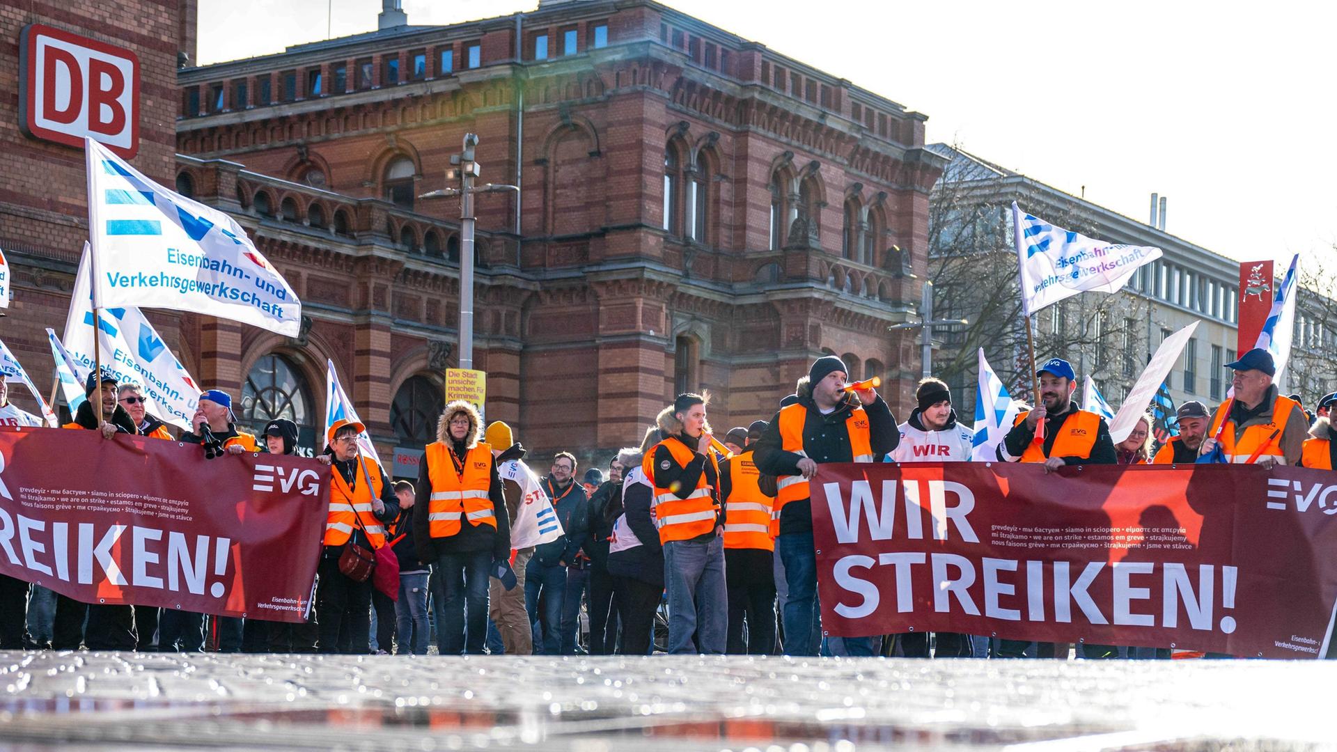 Demonstranten der Eisenbahn- und Verkehrsgewerkschaft (EVG) stehen mit Plakaten vor dem Hauptbahnhof in Bremen. Mit einem großangelegten bundesweiten Warnstreik legen die Gewerkschaften EVG und Verdi weite Teile des öffentlichen Verkehrs lahm.
