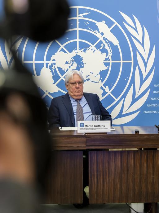 Martin Griffiths und Filippo Grandi von der UN sitzen bei einer Pressekonferenz im UN-Hauptquartier in Genf vor einem großen UN-Logo.