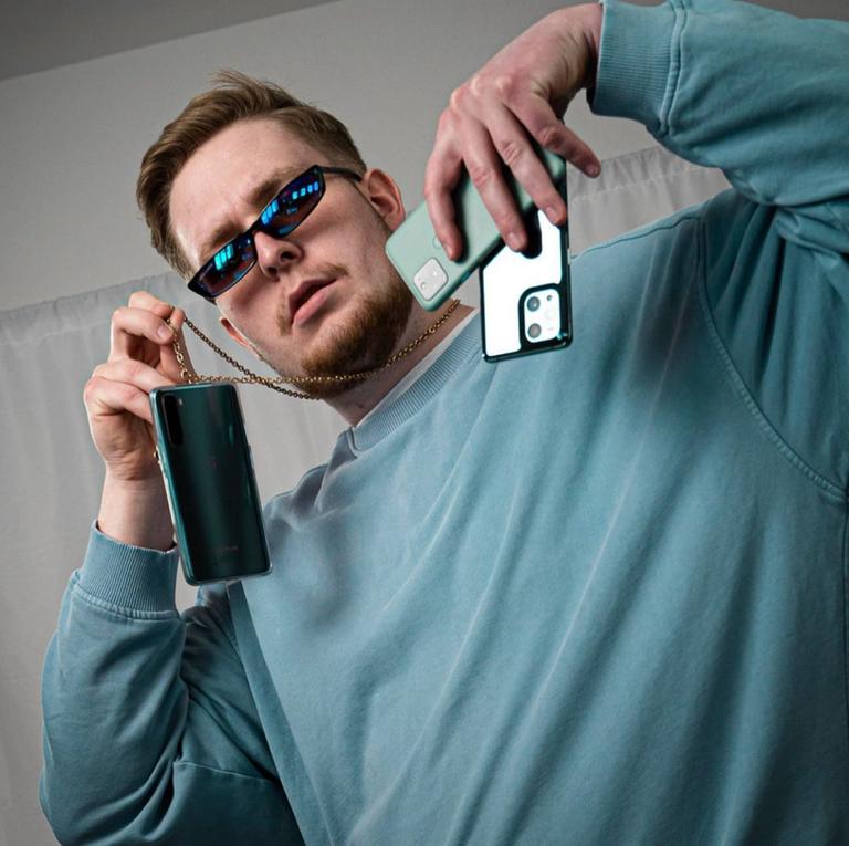 Ein Mann hält drei Smartphones in die Kamera.