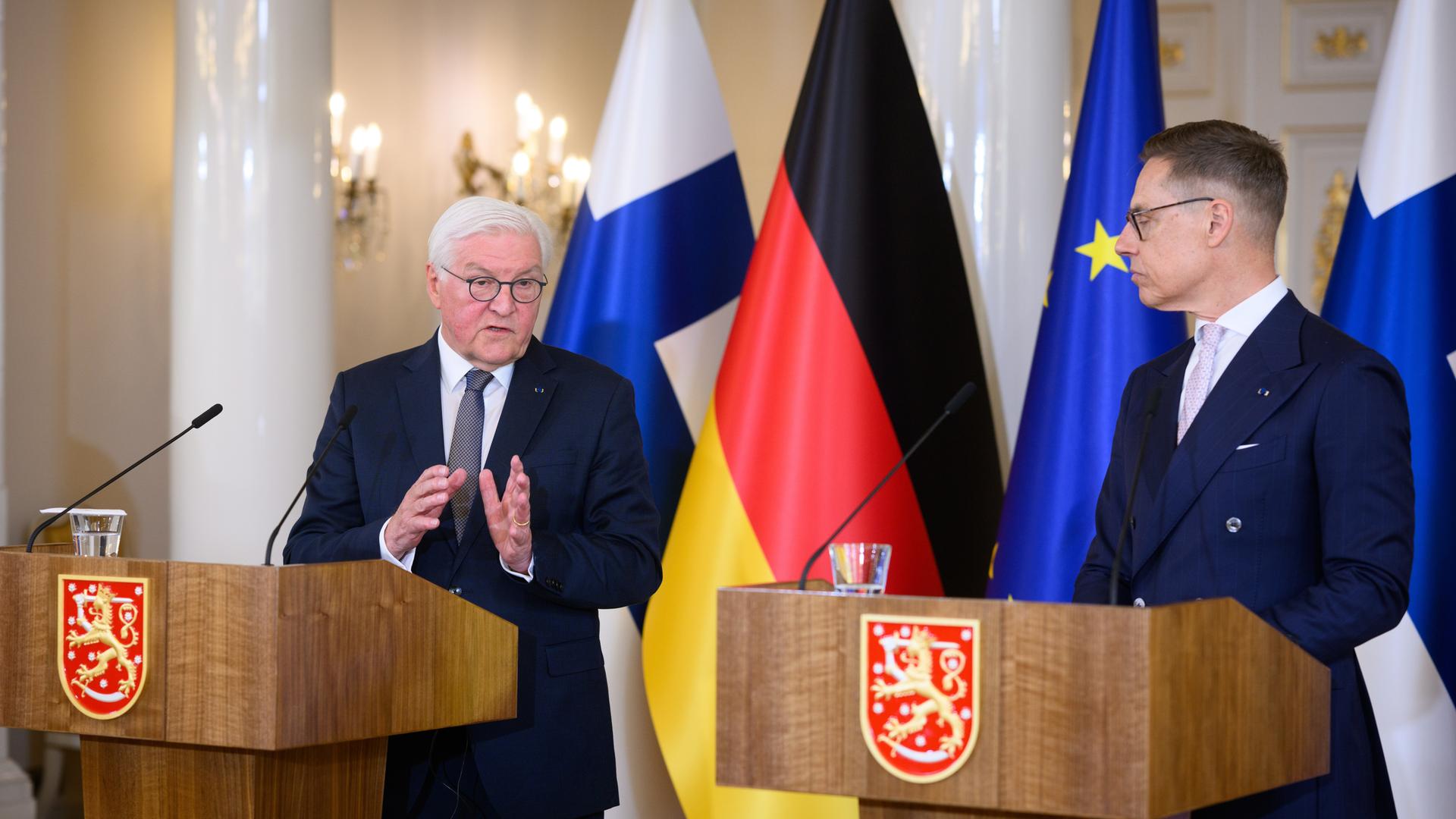 Bundespräsident Steinmeier (l) und der finnische Präsident Stubb äußern sich bei einer Pressekonferenz. Sie tragen beide einen dunklen Anzug und stehen an hölzernen Pulten mit Mikrofon. 