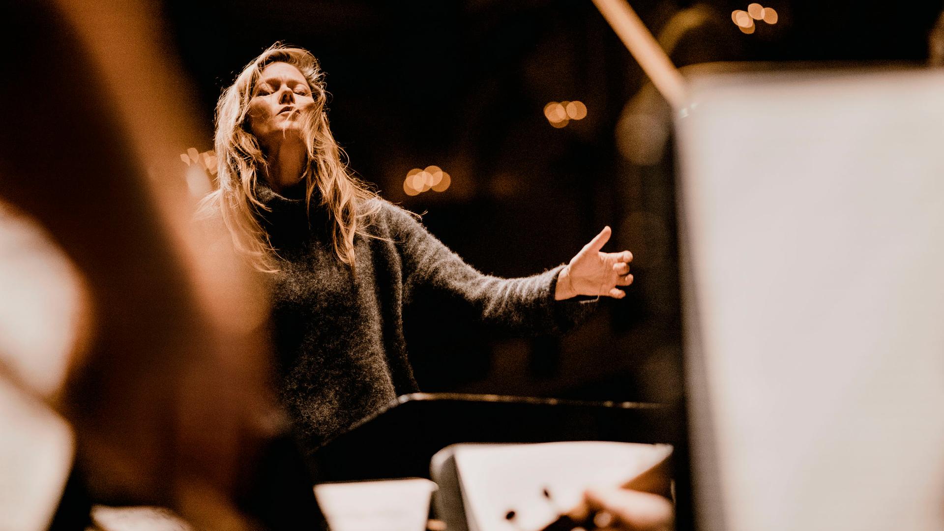 Barbara Hannigan dirigiert ein Orchester mit geschlossenen Augen und legt in diesem Moment den Kopf ein wenig nach hinten.