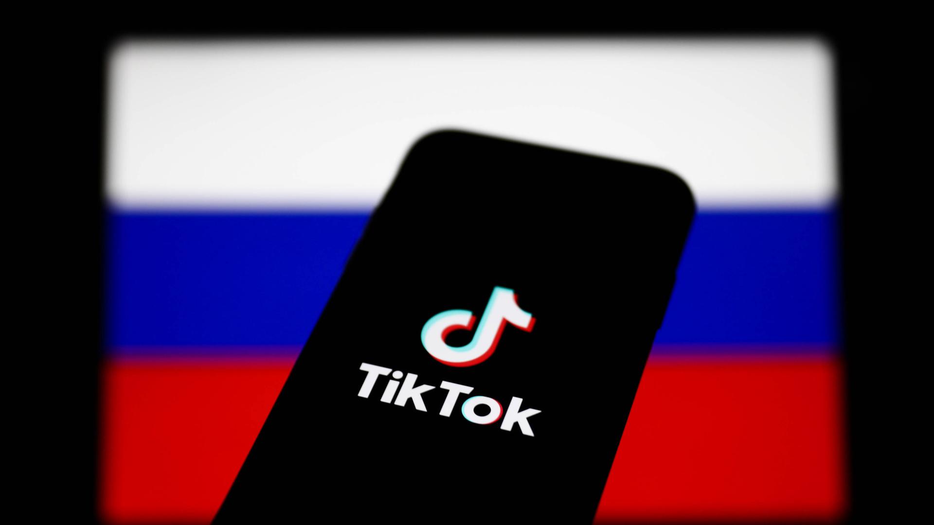 Ein Smartphone mit dem Logo von TikTok vor dem Hintergrund einer russischen Flagge 