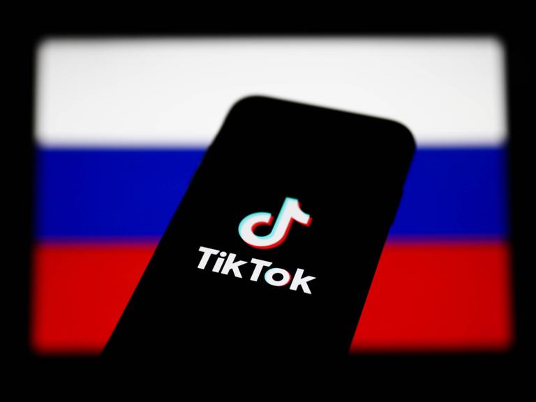 Ein Smartphone mit dem Logo von TikTok vor dem Hintergrund einer russischen Flagge 