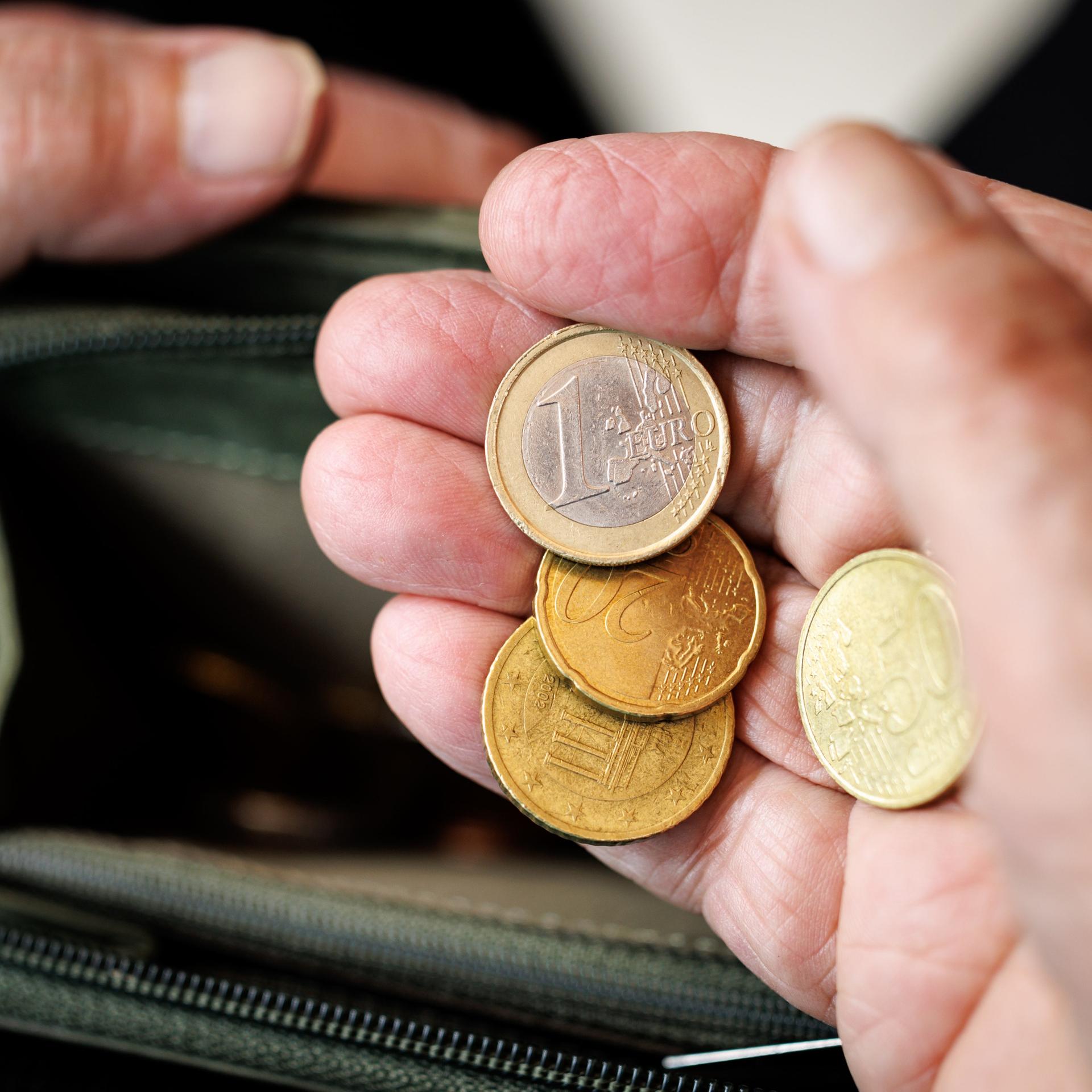 Eine ältere Dame zählt in ihren Händen das Geld aus ihrem Geld-Beutel ab.