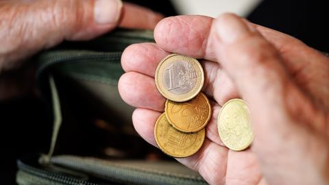 Eine ältere Dame zählt in ihren Händen das Geld aus ihrem Geld-Beutel ab.