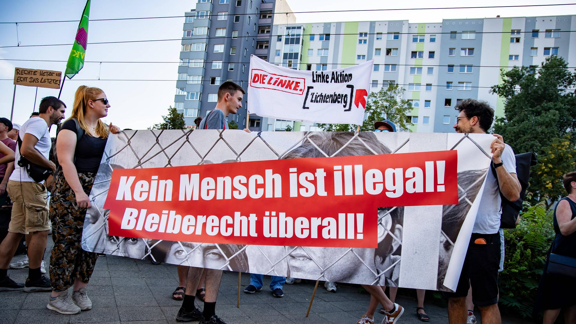 Zwei Menschen halten einen Banner mit der Aufschrift "Kein Mensch ist illegal".