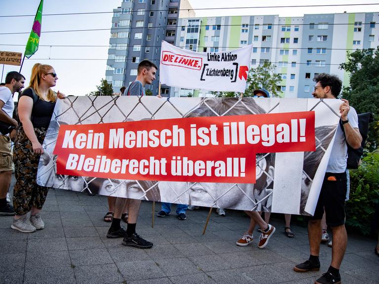 Zwei Menschen halten einen Banner mit der Aufschrift "Kein Mensch ist illegal".