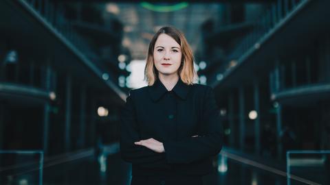 Die Bundestagsabgeordnete Annika Klose steht selbstbewusst mit verschränkten Armen im Bundestag