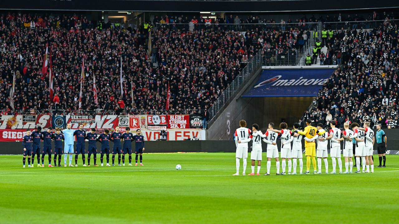 Die Mannschaften von Eintracht Frankfurt und FSV Mainz 05 stehen am 21.12.24 nach den Ereignissen in Magdeburg für eine Gedenkminute auf dem Platz.