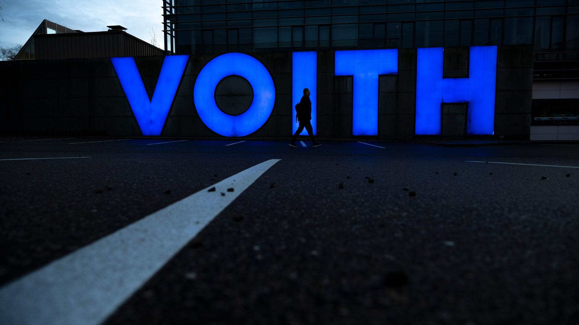 Der Schatten eines Menschen zeichnet sich an der Firmenzentrale von Voith im Firmenlogo ab. 