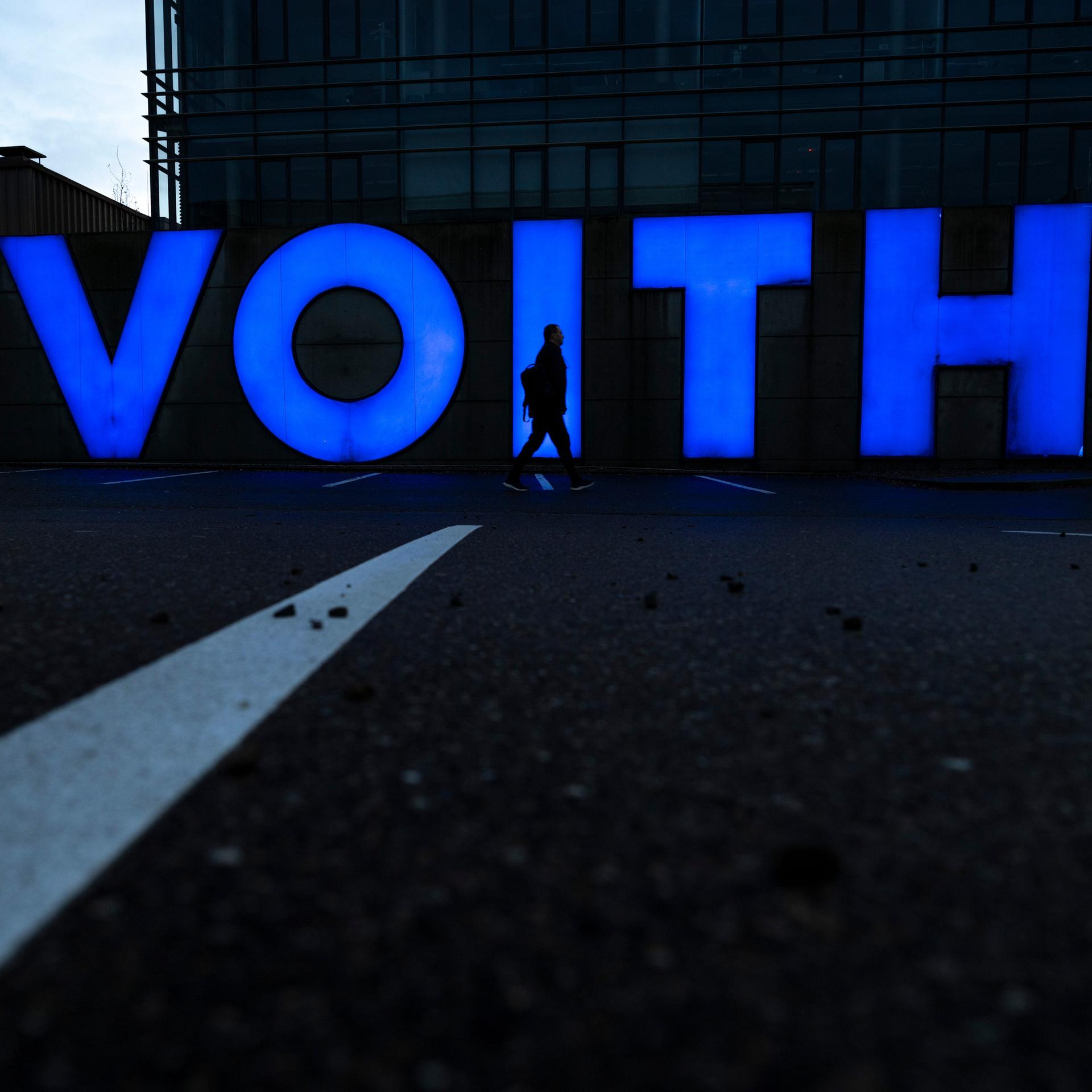 Der Schatten eines Menschen zeichnet sich an der Firmenzentrale von Voith im Firmenlogo ab. 