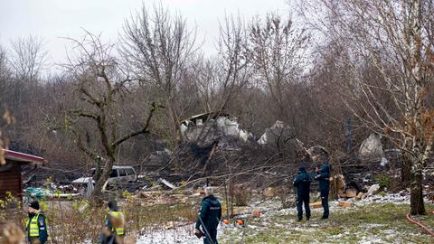 Mitarbeiter des litauischen Katastrophenschutzministeriums und Polizeibeamte stehen in der Nähe der Stelle, an der ein DHL-Frachtflugzeug in ein Haus nahe der litauischen Hauptstadt Vilnius, Litauen, gestürzt ist.