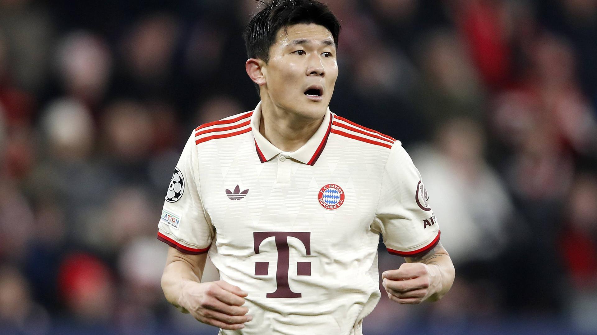 Kim im weißen Trikot mit roten Streifen läuft im Stadion; im Hintergrund unscharf eine vollbesetzte Zuschauertribüne. 