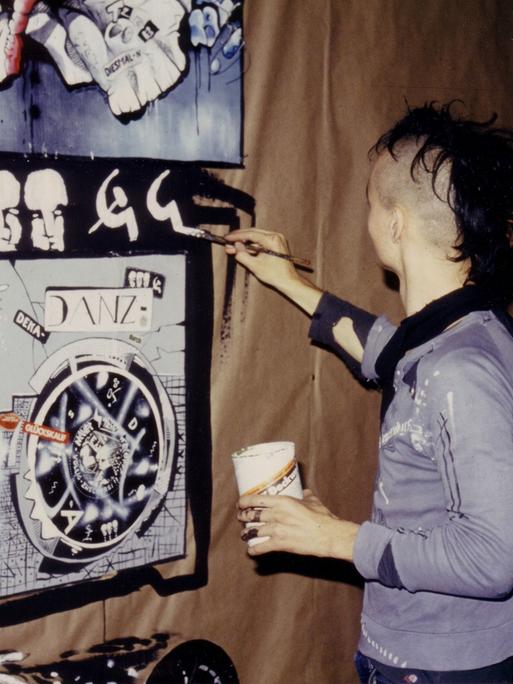 Aufnahme von 1986: Der Punk Igor Tatschke aus der DDR steht vor einer Wand und malt darauf