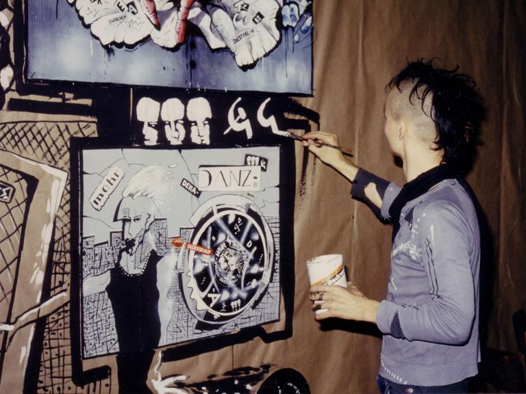 Aufnahme von 1986: Der Punk Igor Tatschke aus der DDR steht vor einer Wand und malt darauf