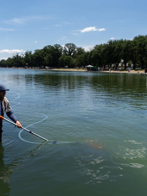 Ein Mensch steht in Washington in einem Wasserbecken und benutzt ein Reinigungsgerät.