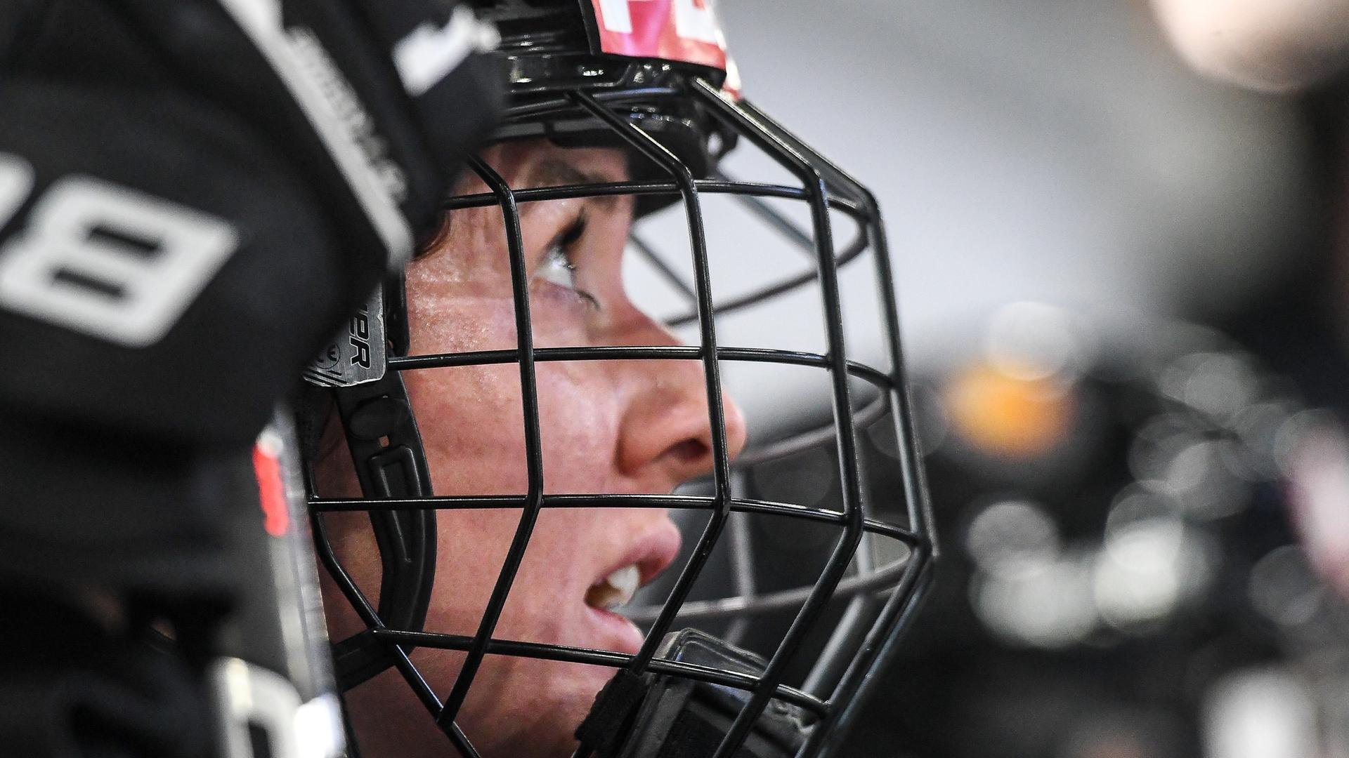 Die deutsche Eishockey-Nationalspielerin Daria Gleißner schaut auf das Spielfeld. Sie trägt einen Helm, ihr Gesicht ist hinter einer Maske geschützt. 