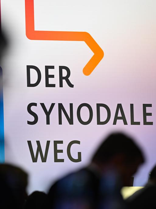 Teilnehmer der Synodalversammlung sitzen vor dem Schriftzug "Der Synodale Weg".