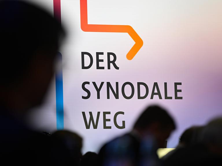 Teilnehmer der Synodalversammlung sitzen vor dem Schriftzug "Der Synodale Weg".