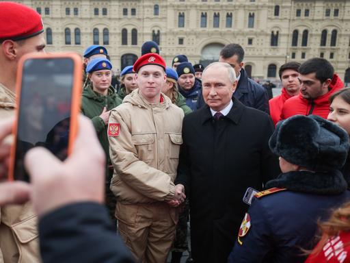 Der russische Präsident Wladimir Putin, begegnet russischen Bürgerinnen und Bürgern. Er ist umgeben von Sicherheitskräften.