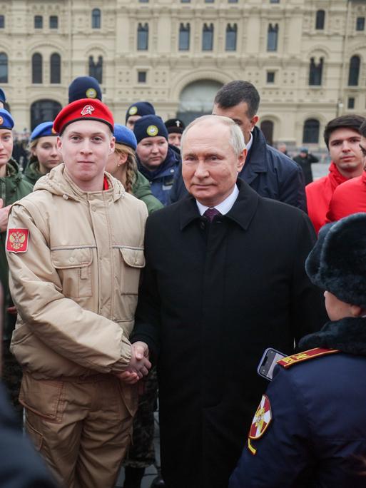 Der russische Präsident Wladimir Putin, begegnet russischen Bürgerinnen und Bürgern. Er ist umgeben von Sicherheitskräften.