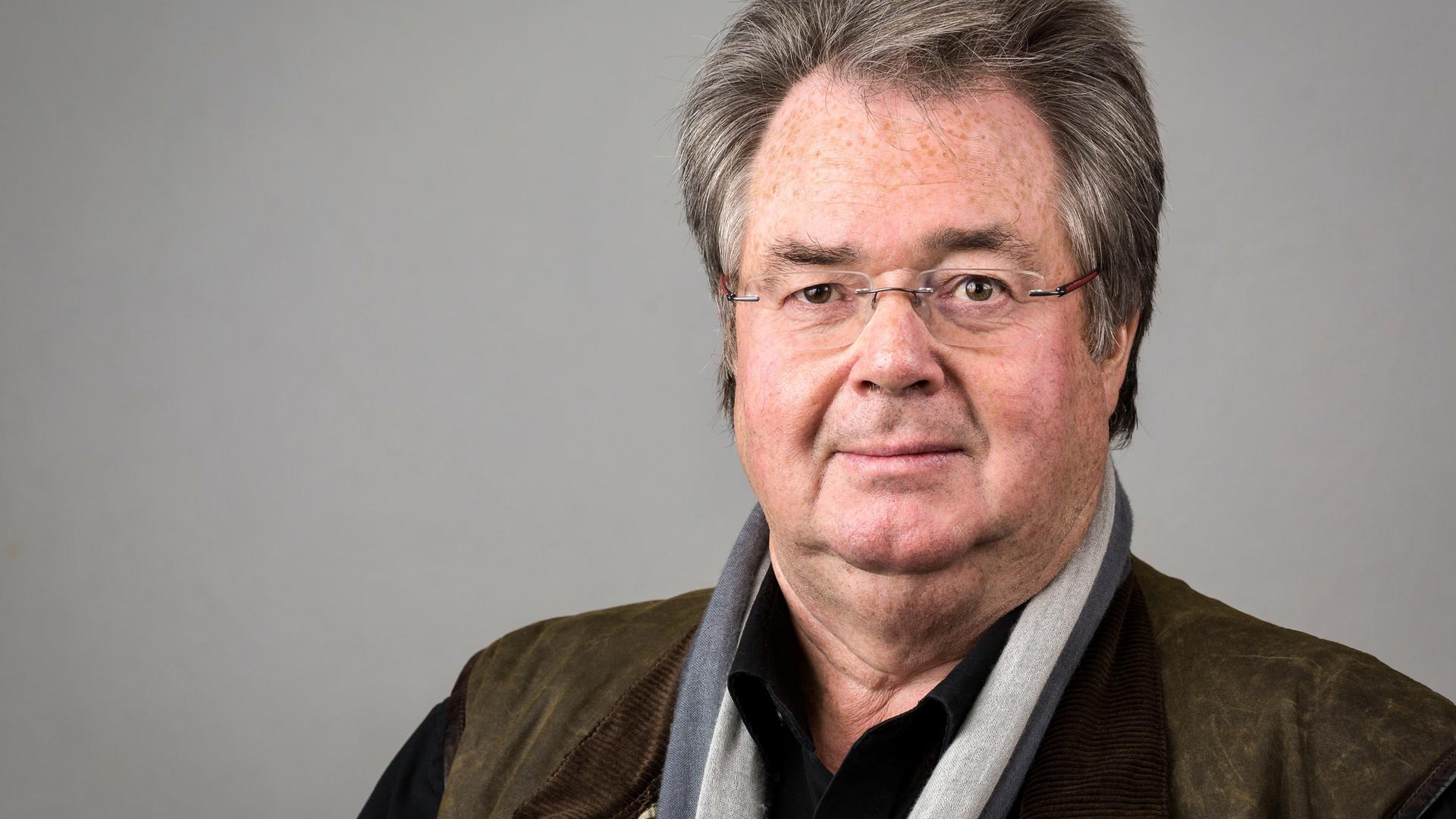 Ein Mann mit kurzem grauen Haar und Brille blickt mit leichtem Lächeln die Kamera. Ein Mann mit kurzem grauen Haar und Brille blickt mit leichtem Lächeln die Kamera.