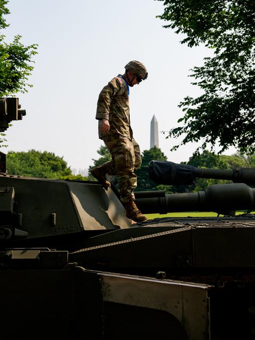 M1 Alpha a3, Abrams Panzer, Stryker und M2 Bradley: Ein US-Soldat steigt über Kampffahrzeuge. Im Hintergrund ist das Washington Monument zu sehen