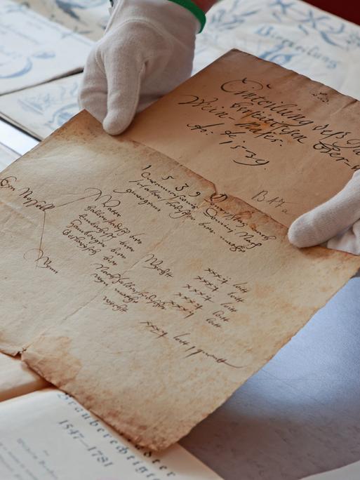 Historische Dokumente werden in einer Ausstellung im Stadtarchiv Halberstadt gezeigt. Eine Person hält ein Dokument hin. Es ist ein altes Papier.