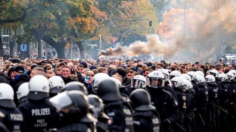 Die Fans des Hamburger SV gehen von der Polizei begleitet zum Stadion und brennen Pyrotechnik ab.