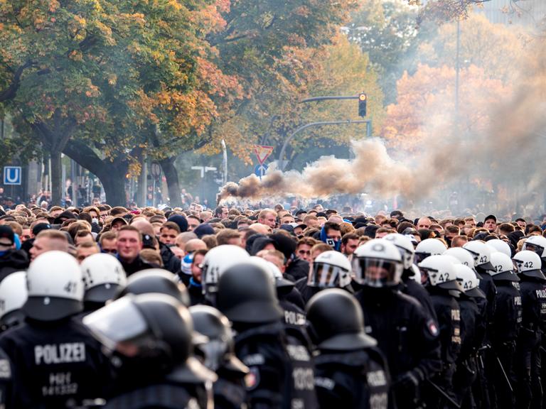 Die Fans des Hamburger SV gehen von der Polizei begleitet zum Stadion und brennen Pyrotechnik ab.