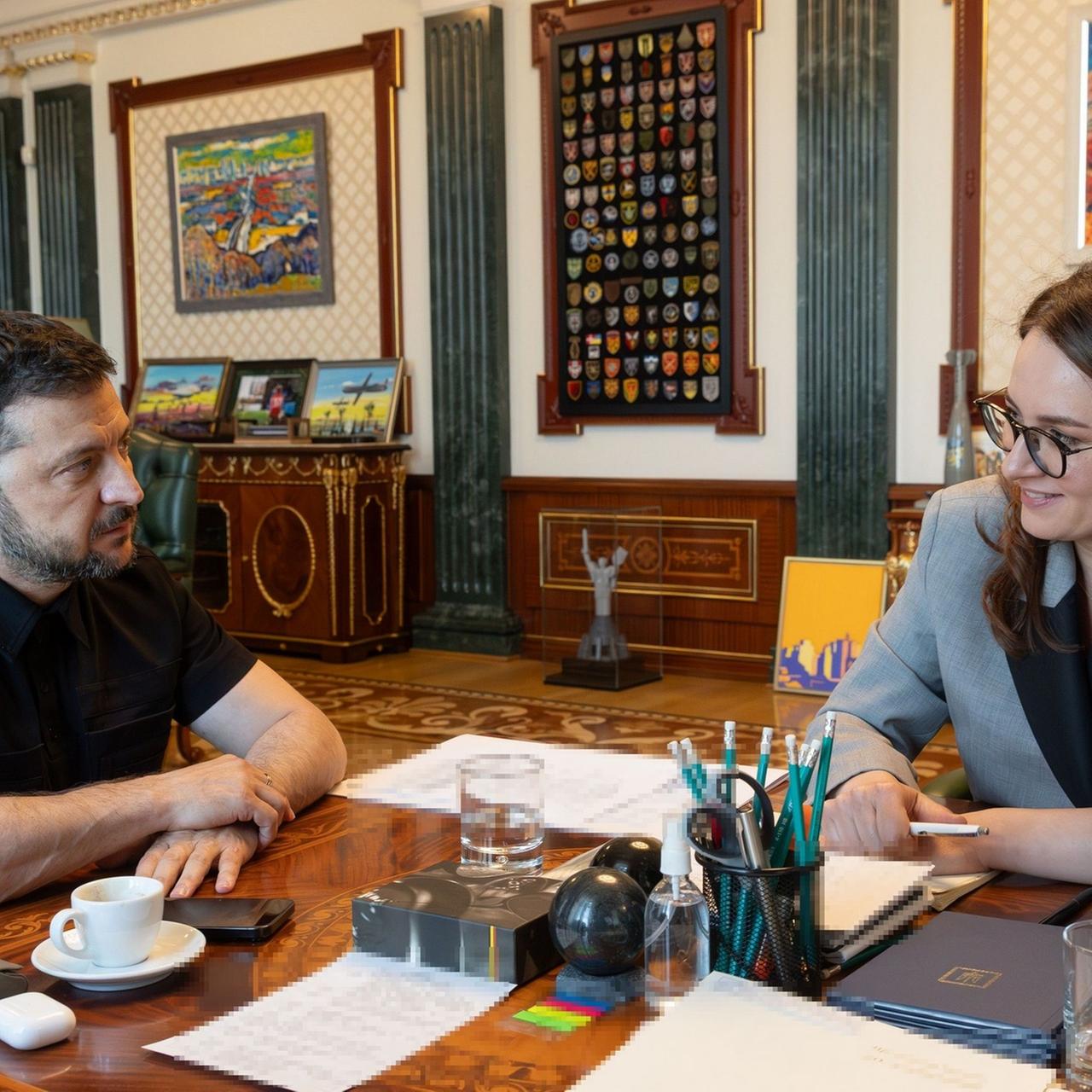 Selenskyj und Swyrydenko sitzen an einem Tisch und schauen sich an.