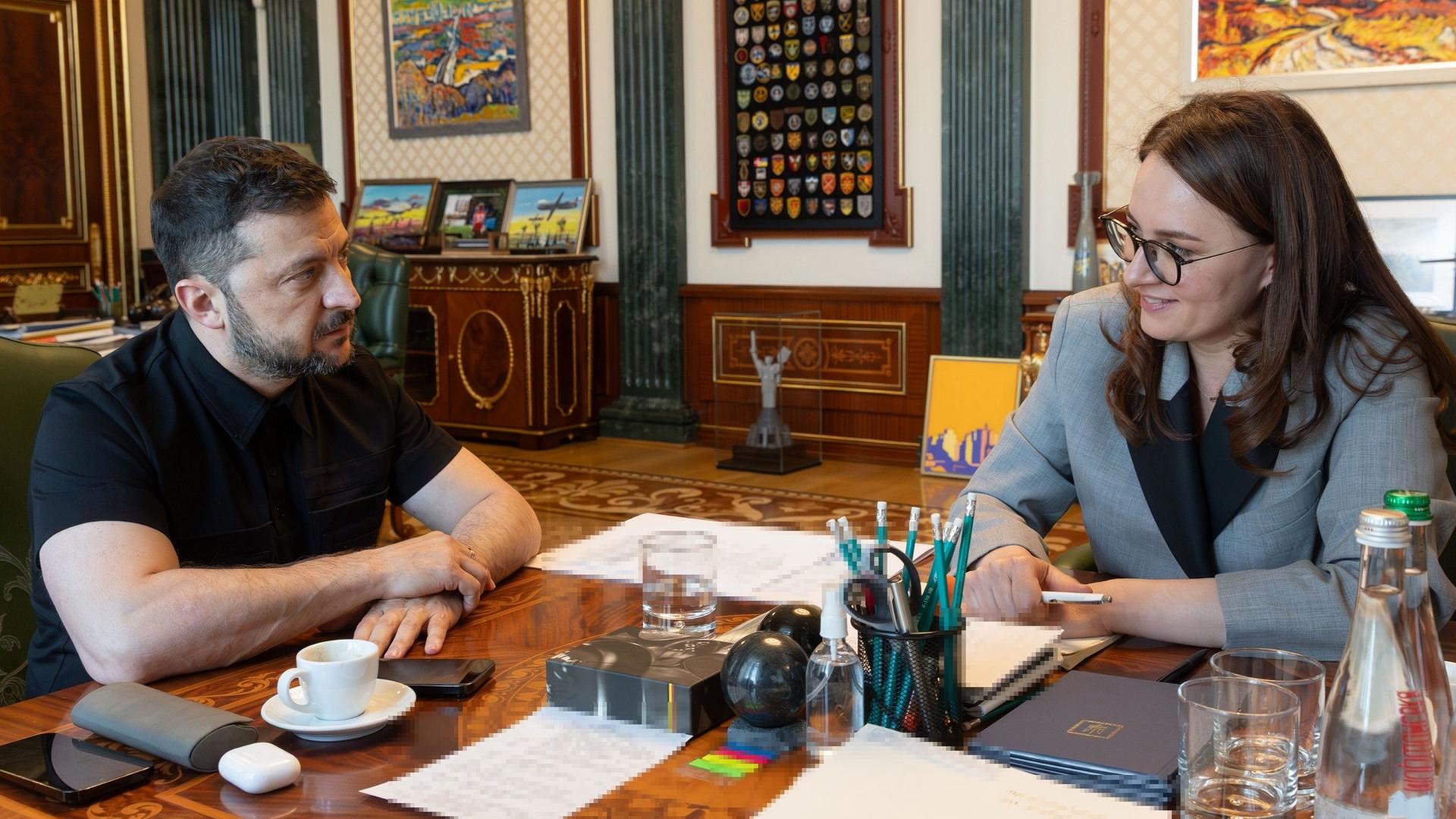 Selenskyj und Swyrydenko sitzen an einem Tisch und schauen sich an.