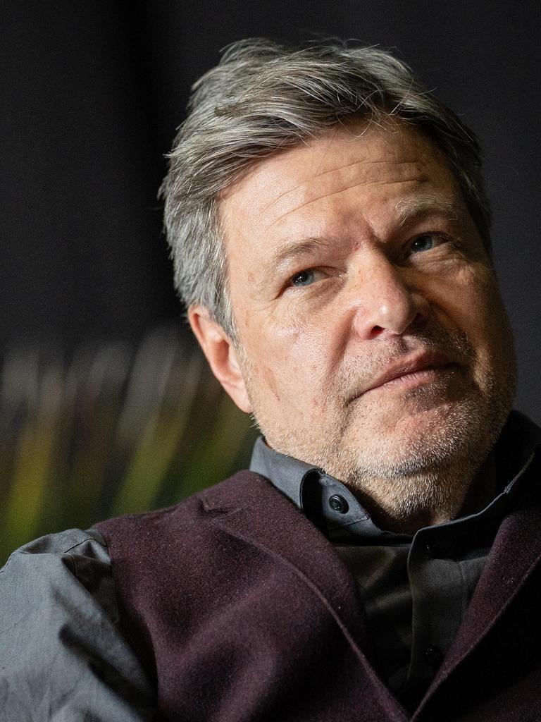 Robert Habeck sitzt mit ernstem Blick vor schwarzem Hintergrund auf einer Bühne