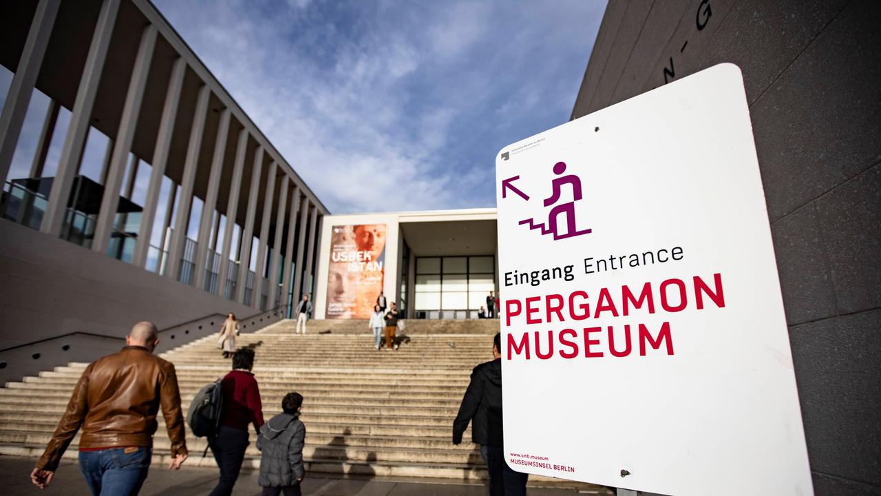 Menschen gehen die Treppe zur James Simon Galerie auf der Berliner Museumsinsel hinauf. Auf einem Schild rechts steht: Eingang Pergamonmuseum. 