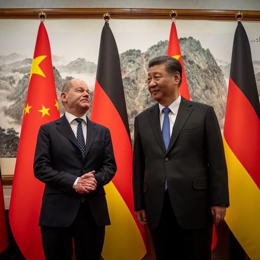 Bundeskanzler Scholz (mit ineinander gelegten Händen) und der chinesische Staatspräsident Xi Jinping posieren vor den Flaggen Deutschlands und Chinas.
